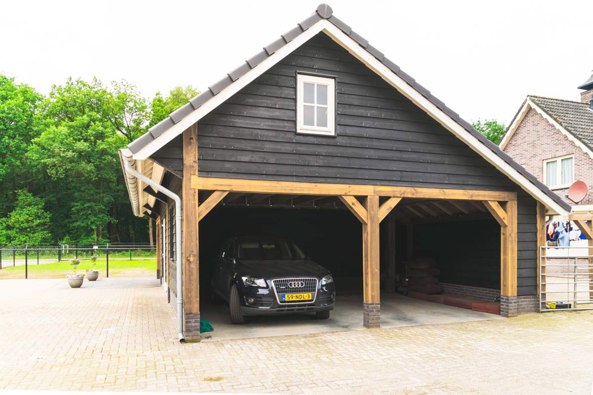 Haat Mount Bank lont Zwarte schuur met grote carport en veranda • Houten schuur met overkapping