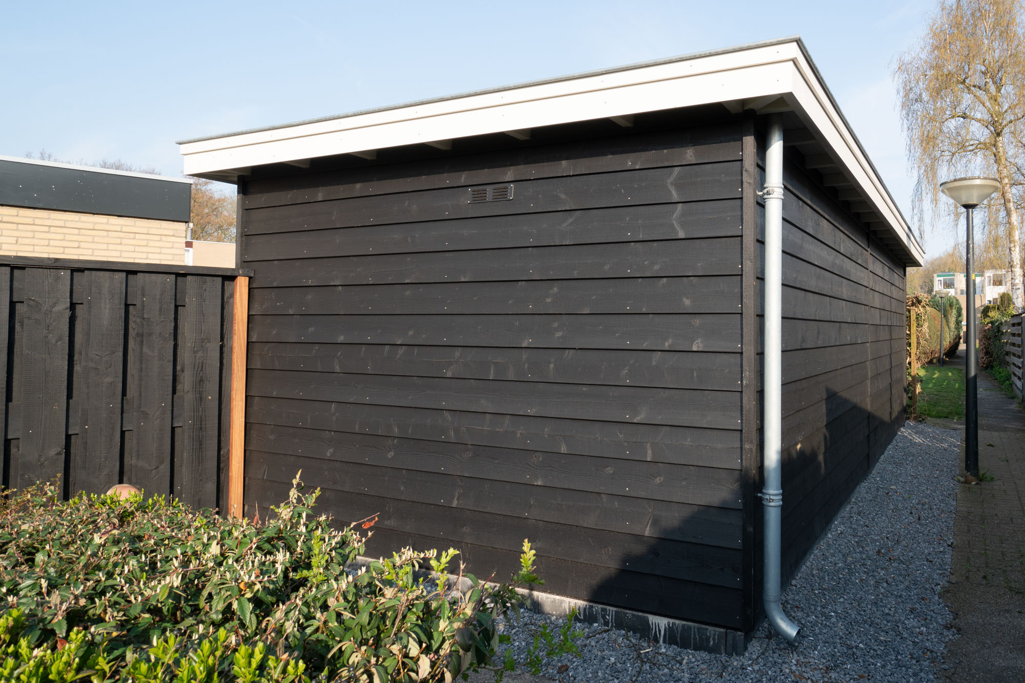 Houten schuur met plat dak en overkapping